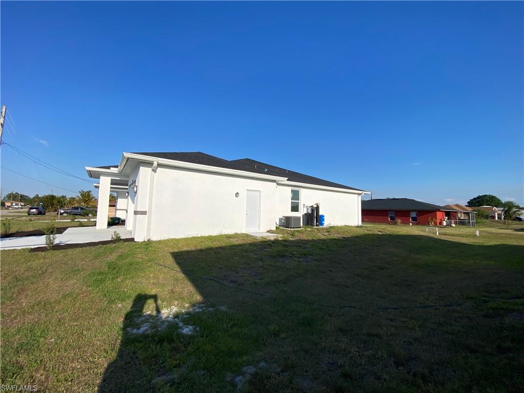 View of home's exterior with a yard, central AC, and stucco siding