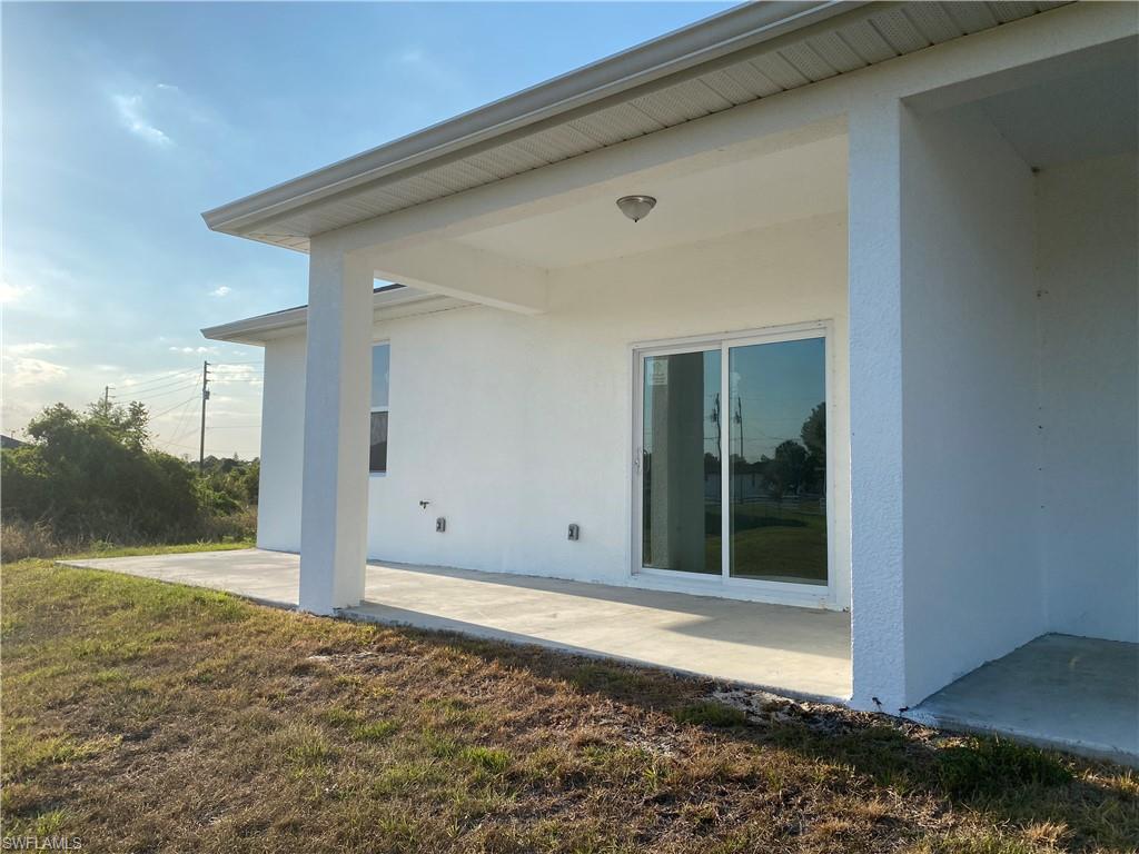 Rear view of house with a patio, a yard, and stucco siding