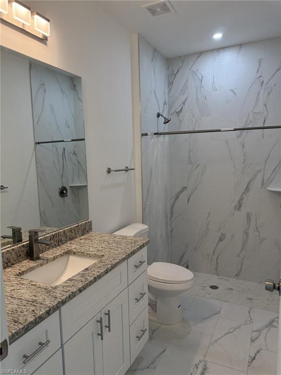 Bathroom featuring marble finish floors, vanity, toilet, a marble finish shower, and recessed lighting