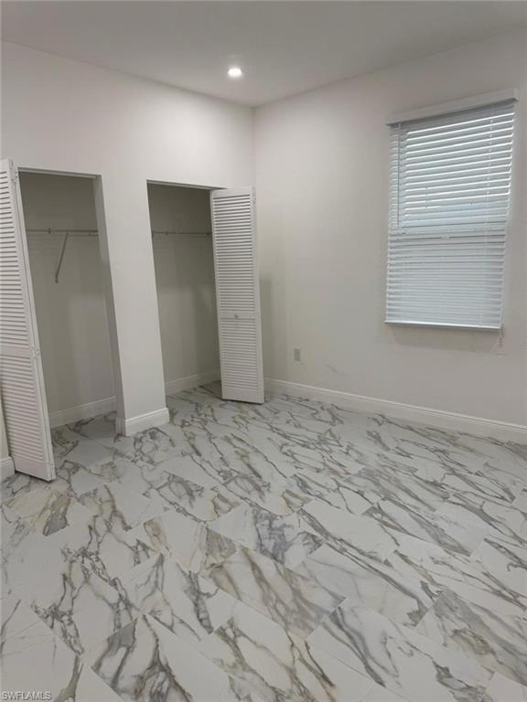Unfurnished bedroom featuring multiple closets, recessed lighting, baseboards, and light marble finish flooring