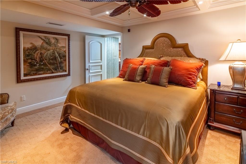 Room featuring a coffered ceiling, wall-to-wall carpeting, and a decorative ceiling fan