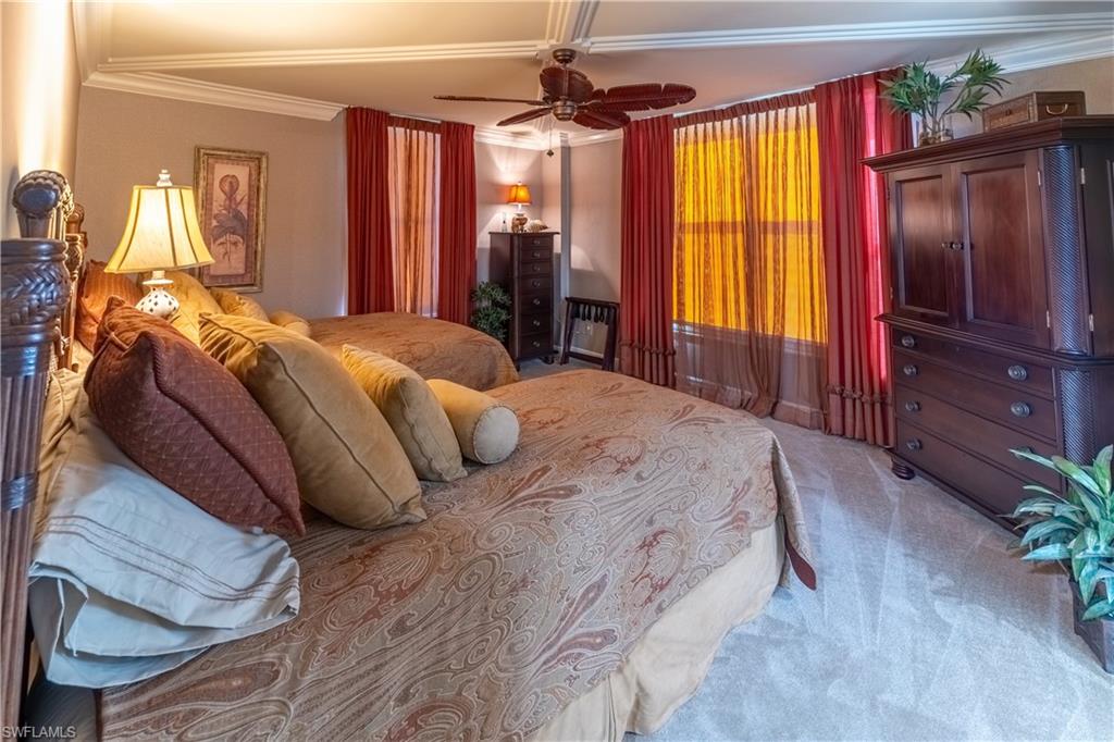 Room featuring crown molding, neutral wall tones, multiple windows with layered window treatments, a ceiling fan, and carpet flooring
