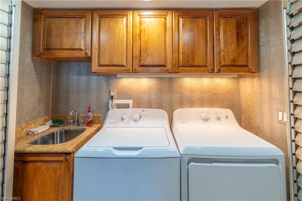 Dedicated laundry area featuring a utility sink with a granite-look countertop, wood-finish cabinetry, and under-cabinet lighting