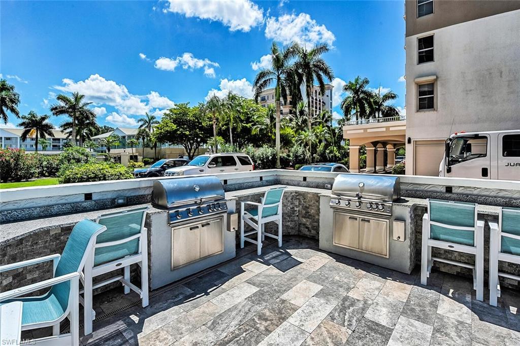 Outdoor grilling station featuring two built-in stainless steel grills, a stone-clad base, and an expansive paver patio