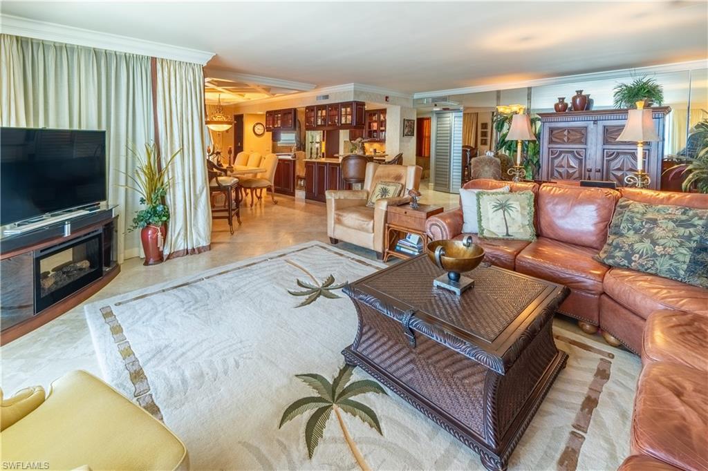Open-concept living space featuring wood-finish flooring, a built-in media console with an electric fireplace, full-height window treatments, and recessed ceiling lighting