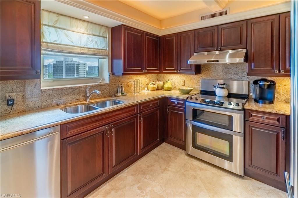 Kitchen featuring rich wood cabinetry, stainless steel appliances, granite countertops, and a double basin sink