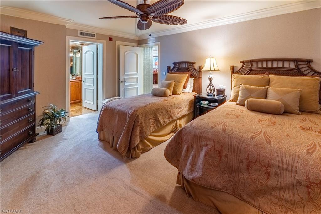 Carpeted interior space featuring a ceiling fan with palm-frond style blades, crown molding, and white paneled doors