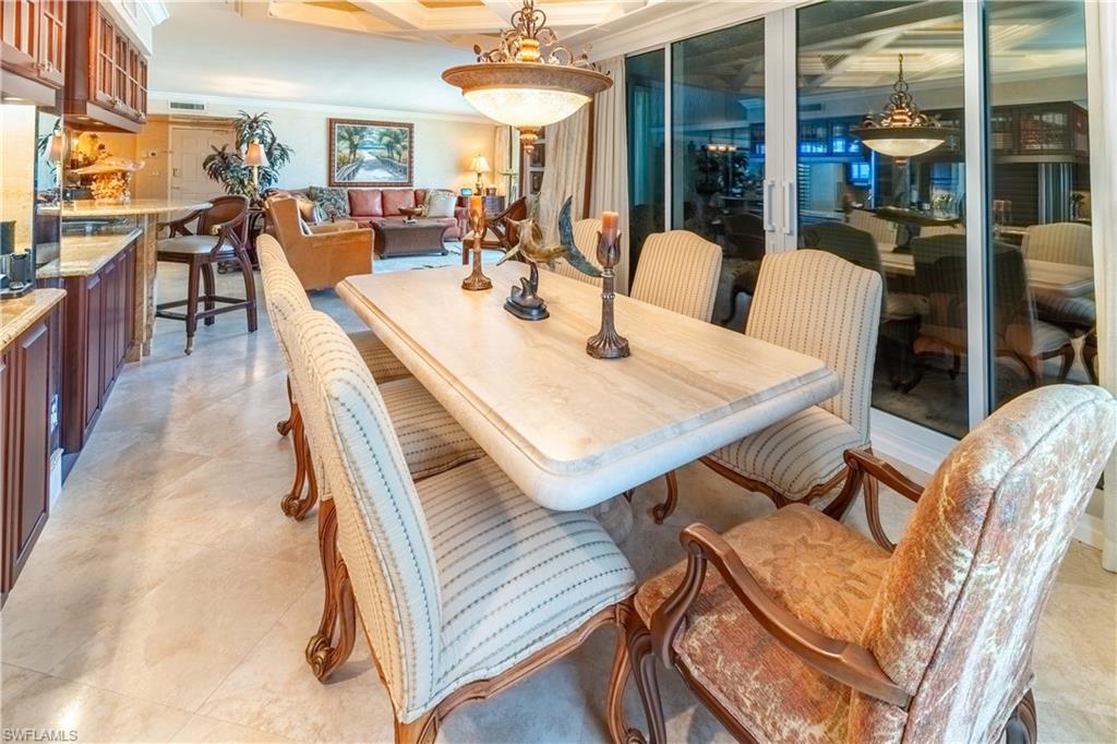 Dining area featuring a coffered ceiling, a large central chandelier, and light-toned tile flooring