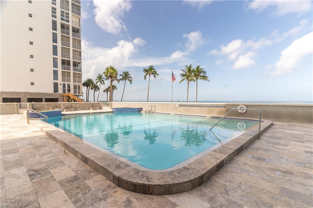 Resort-style swimming pool featuring a tiled edge, integrated spa, and surrounding stone patio