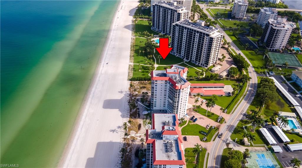 Aerial perspective showcasing beachfront property with white sand and clear turquoise water