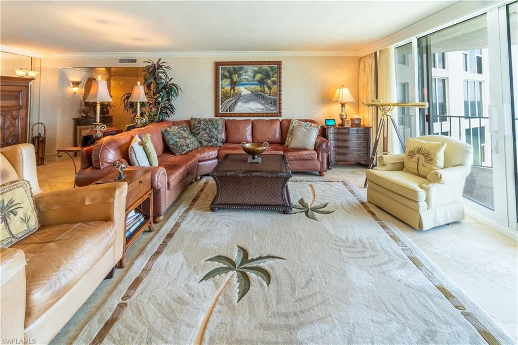 Spacious living area featuring light-toned flooring and a large area rug with palm tree motifs