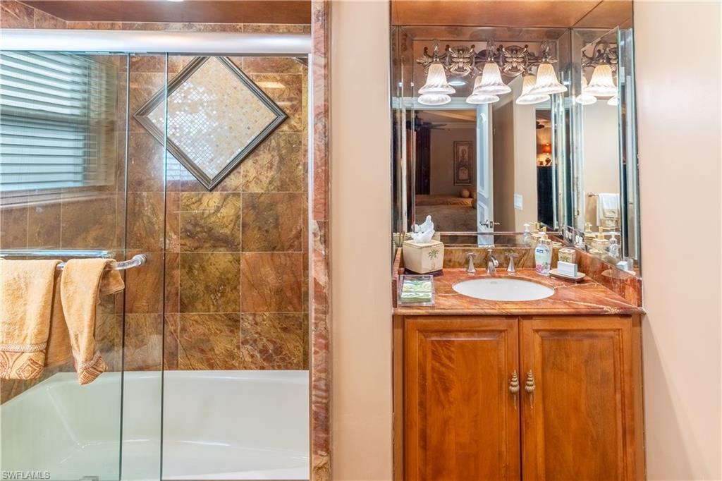 Bathroom vanity with a marble countertop, undermount sink, and wood-finish cabinetry