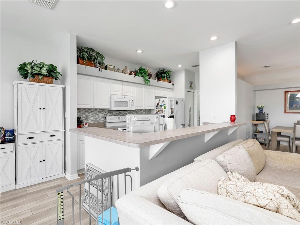 White kitchen cabinetry with a mosaic tile backsplash, light-toned countertops, and recessed lighting