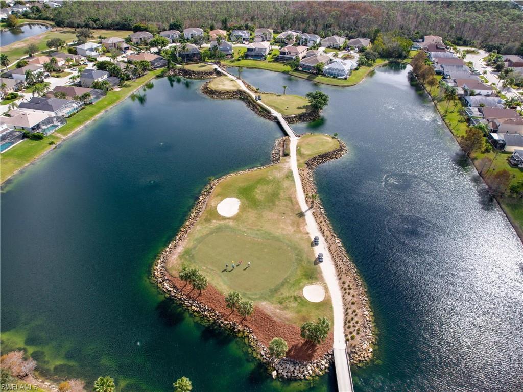 Aerial perspective showcasing a vibrant green golf course island surrounded by a deep blue lake