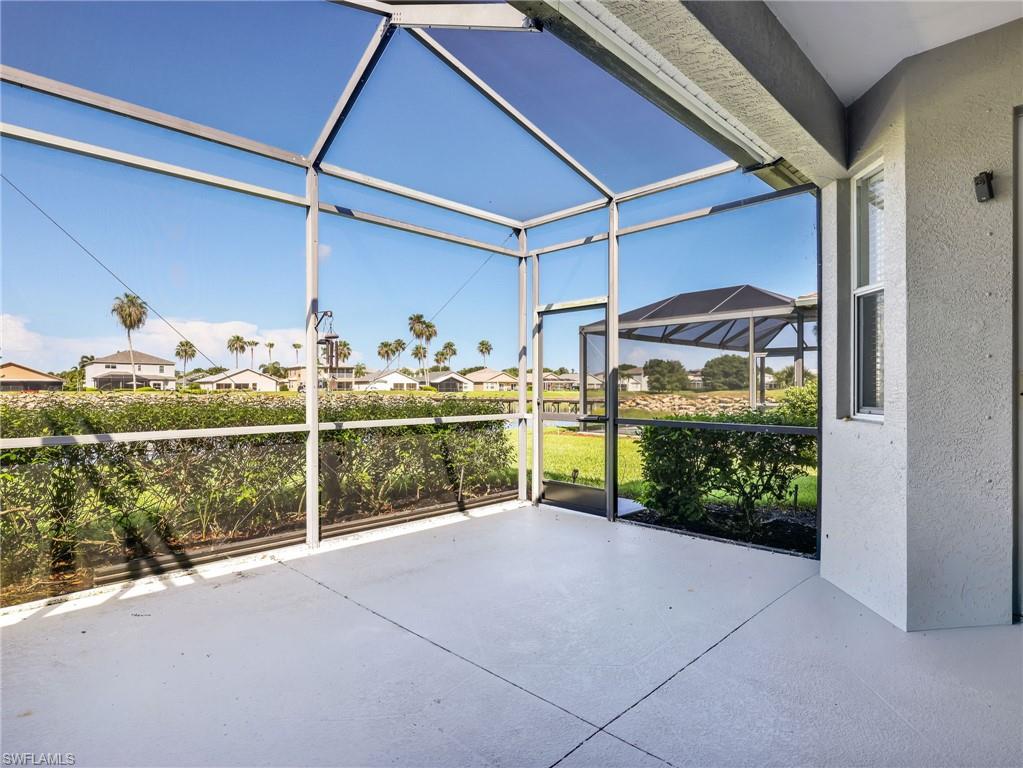 Spacious screened patio featuring a light-toned concrete floor, white frame enclosure, and a screened door