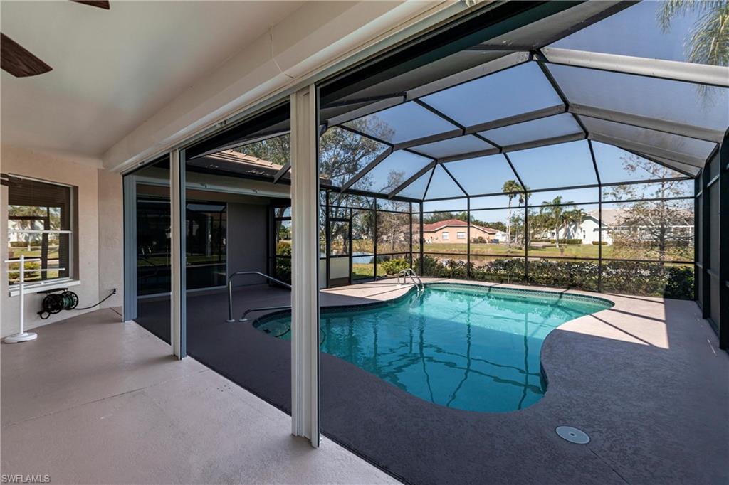 View of lakefront pool on lanai, freshly renovated pool cage and electric shutters cover all opening around pool for privacy- keeps cool in summer, warm on the few chilly days, too!