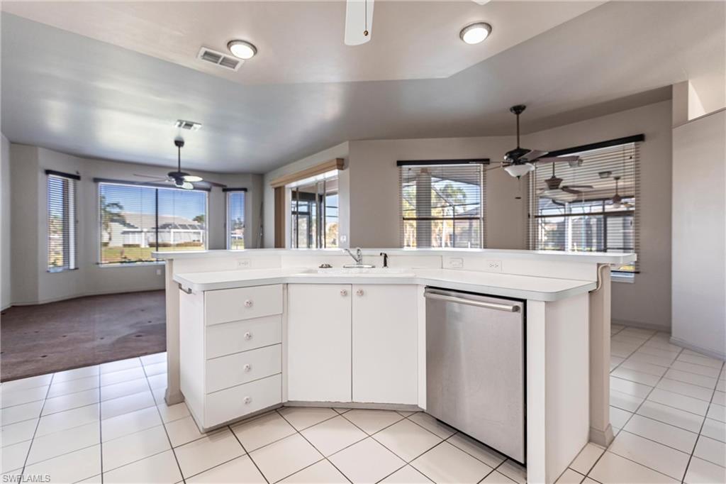 Kitchen with sink, dishwasher, ceiling fan, a kitchen island with sink, and white cabinets. Windowed eat-in dining area. Large pocket sliders lead to lanai. Views everywhere!