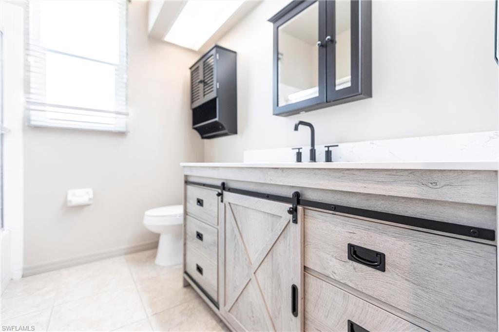 Bathroom featuring vanity, comfort height toilet, and tile patterned flooring with hurricane rated windows.