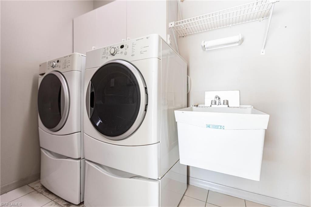 Laundry featuring front load washing machine and dryer and utility sink.