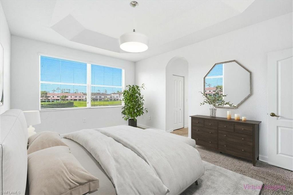 Bright bedroom featuring a tray ceiling with recessed lighting and a central ceiling fixture