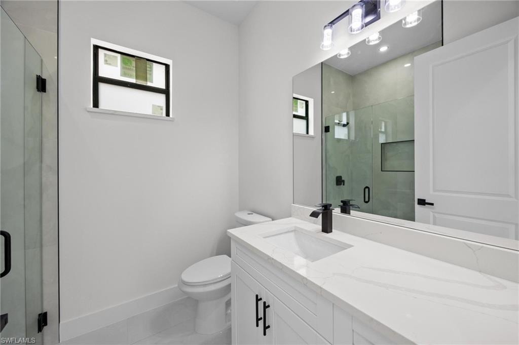 Modern bathroom featuring a white vanity with a quartz countertop and integrated sink, matte black faucet, and frameless mirror