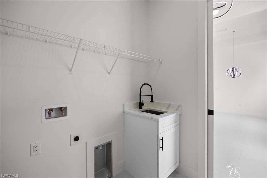 Utility room featuring a built-in sink with a black matte faucet, white cabinetry, and a light-toned countertop