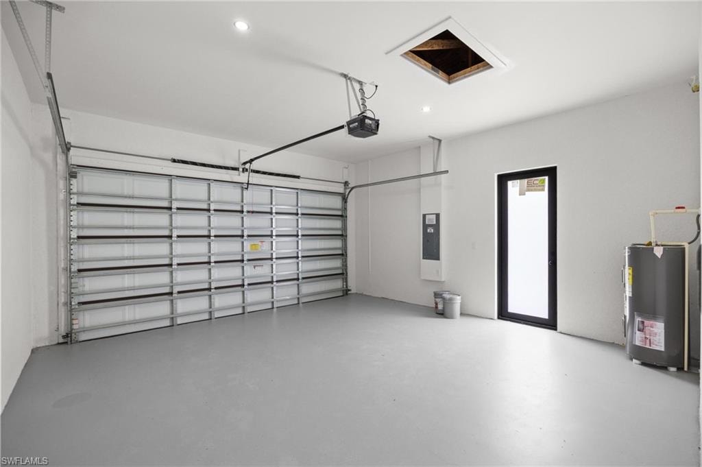 Spacious garage with a sectional overhead door, gray finished flooring, recessed lighting, and a black-framed access door