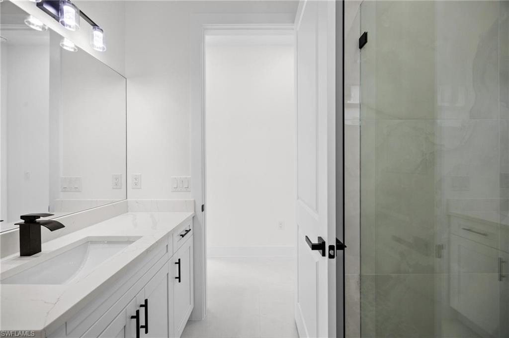 Bathroom vanity featuring a single integrated sink, stone-finish countertop, and black fixtures