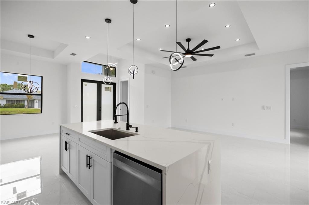 Contemporary kitchen island featuring a waterfall countertop, undermount sink with a gooseneck faucet, and integrated dishwasher