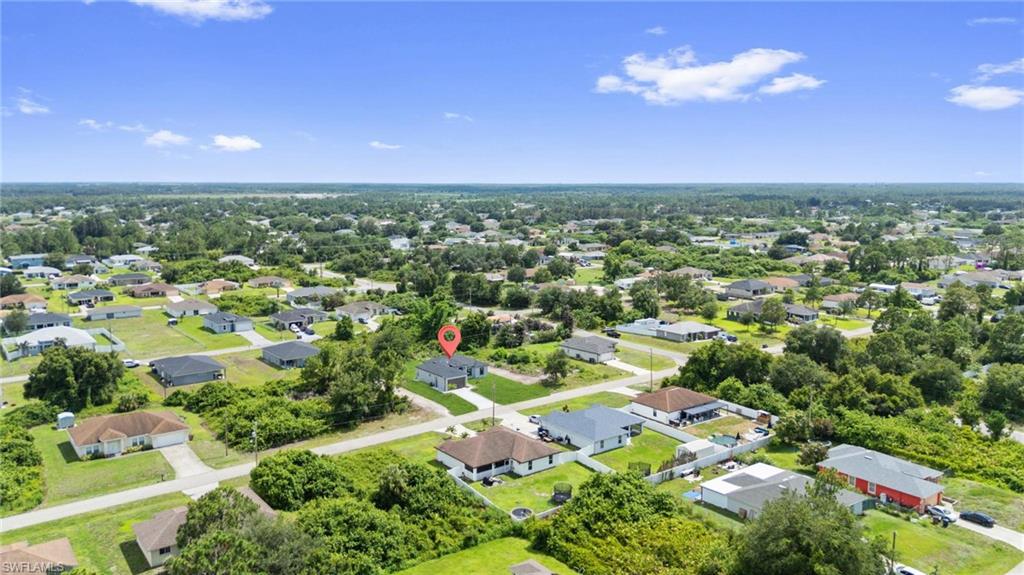 Aerial perspective showcasing a residential neighborhood with single-story homes, mature trees, and paved streets