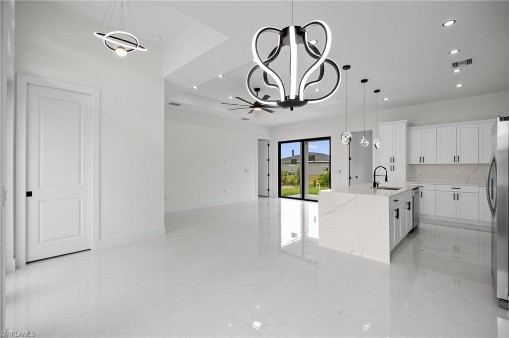 Open-concept living area featuring a modern kitchen with a waterfall island, white cabinetry, and stainless steel appliances