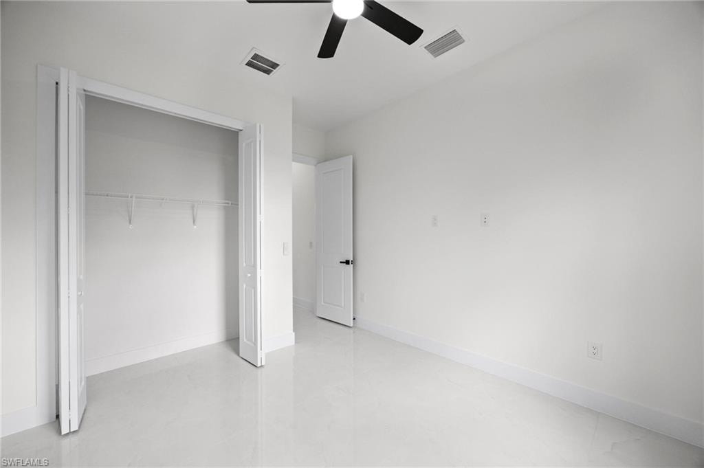 Room featuring light-toned flooring, white walls, and a ceiling fan