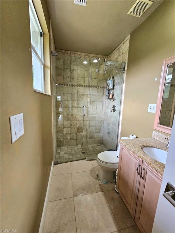 Full bathroom featuring a glass-enclosed shower with tiled walls and flooring