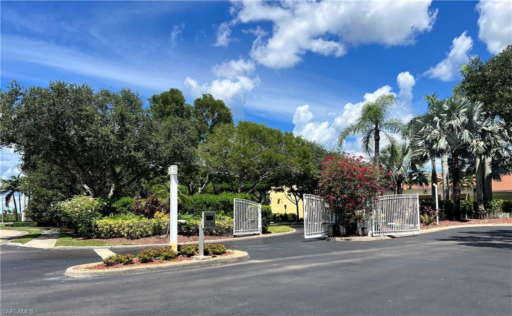View of asphalt road with a gate, curbs, and a gated entry