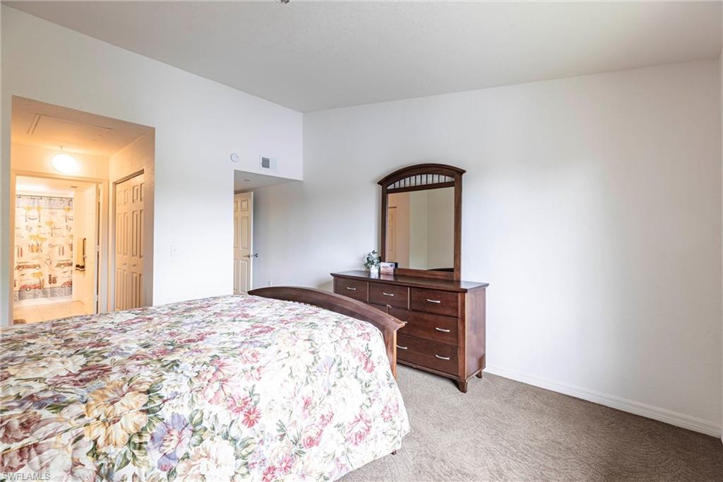 Bedroom featuring light carpet, attic access, and ensuite bath