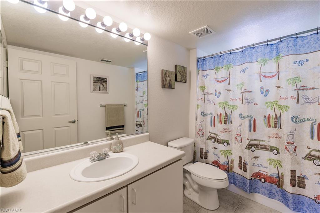 Full bathroom featuring a textured ceiling, tile patterned flooring, vanity, and curtained shower