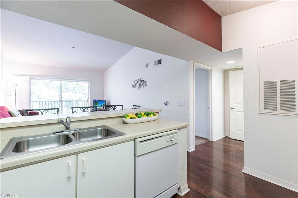 Kitchen with white dishwasher, light countertops, dark wood finished floors, and white cabinets