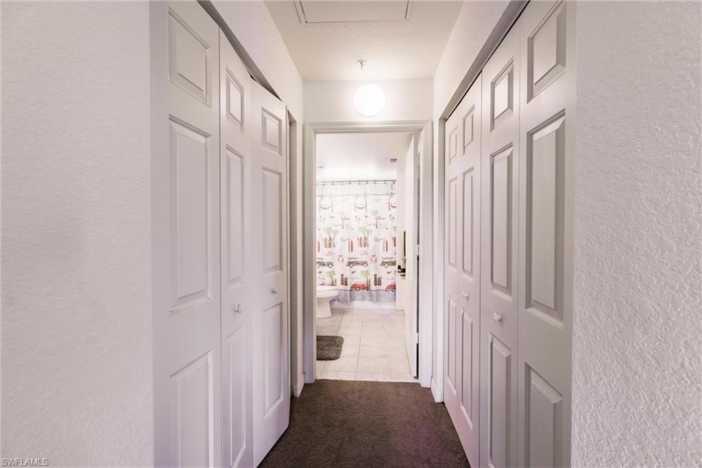 Hallway featuring a textured wall, dark tile patterned flooring, and dark carpet