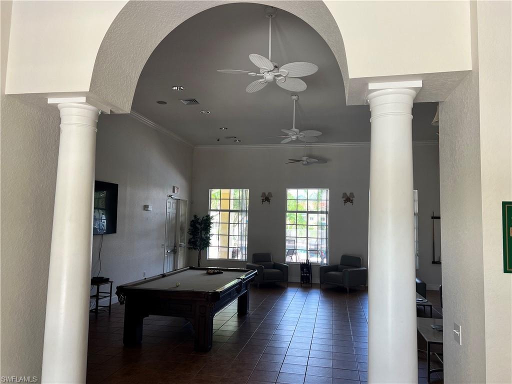 Playroom with ornate columns, a textured wall, ornamental molding, a ceiling fan, and pool table