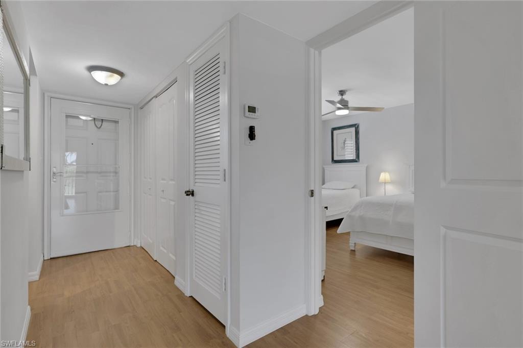 Entryway featuring wood-finish flooring, white walls, and a white front door with a glass panel