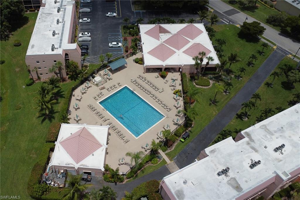 Community amenities including a rectangular pool with surrounding lounge chairs, a shaded pavilion, and lush green spaces