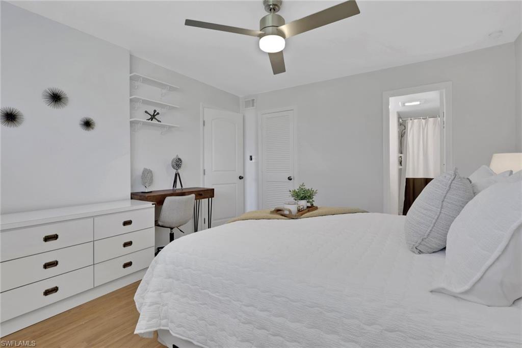 Bedroom featuring wood-finish flooring, a contemporary ceiling fan with integrated lighting, and a built-in white dresser