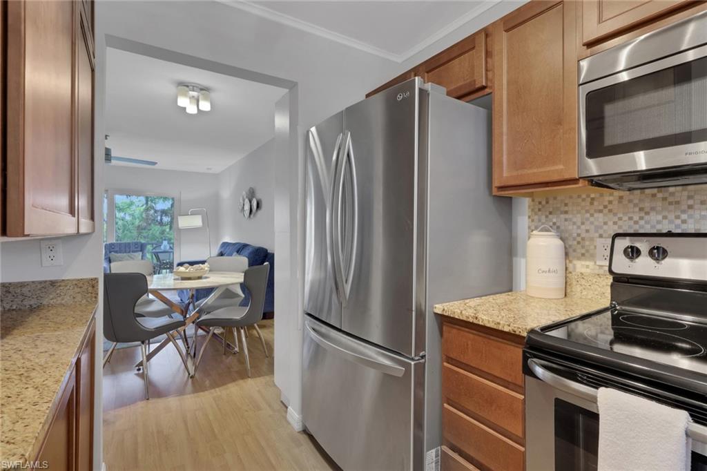 Kitchen featuring granite-style countertops, mosaic tile backsplash, and wood-finish cabinetry