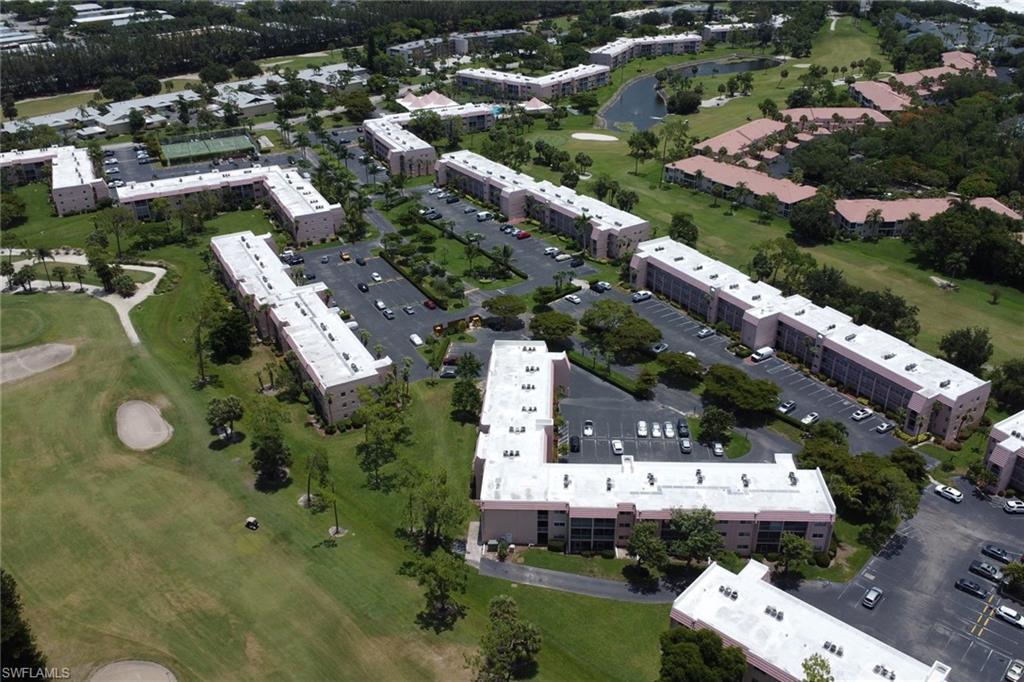 Expansive multi-building residential complex featuring ample parking, mature landscaping, and an integrated golf course