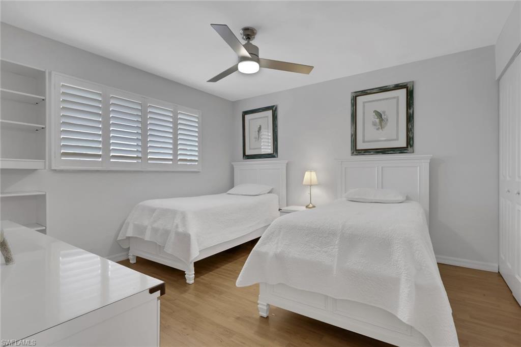 Room featuring wood-finish flooring, a contemporary ceiling fan, and built-in shelving