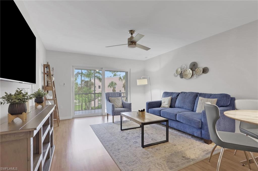 Living area featuring light wood-finish flooring, white walls, and a ceiling fan