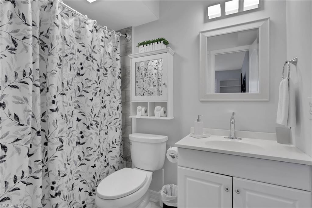 Bathroom featuring a white vanity with a single sink, white framed mirror, and a three-light fixture