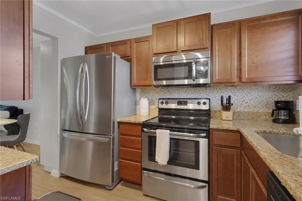 Kitchen featuring wood cabinetry, light speckled countertops, and a mosaic tile backsplash