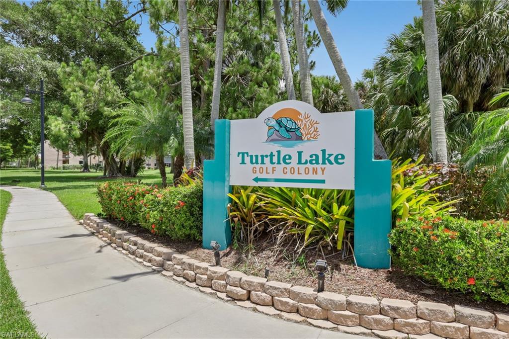Turtle Lake Golf Colony signage featuring a decorative stone retaining wall and lush tropical landscaping