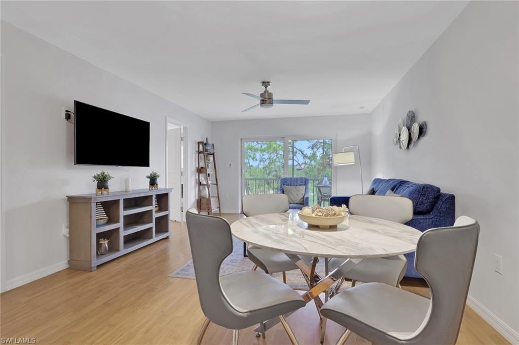 Open-concept living area with wood-finish flooring, a contemporary ceiling fan, and sliding glass doors providing natural light